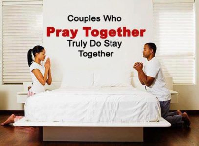 A male and a female kneeling on either side of a bed with white sheets facing each other they are definately finding times to pray